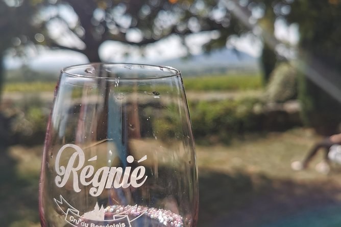 A wine glass engraved Régnié, vines out of focus behind it