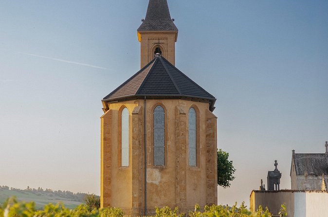A small golden-stone chapel with a slate spire in evening light
