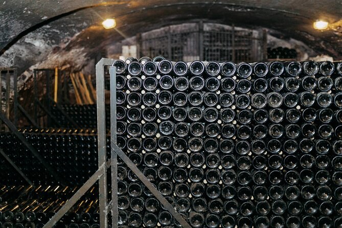 Hundreds of bottles stacked in a cage in a vaulted cellar